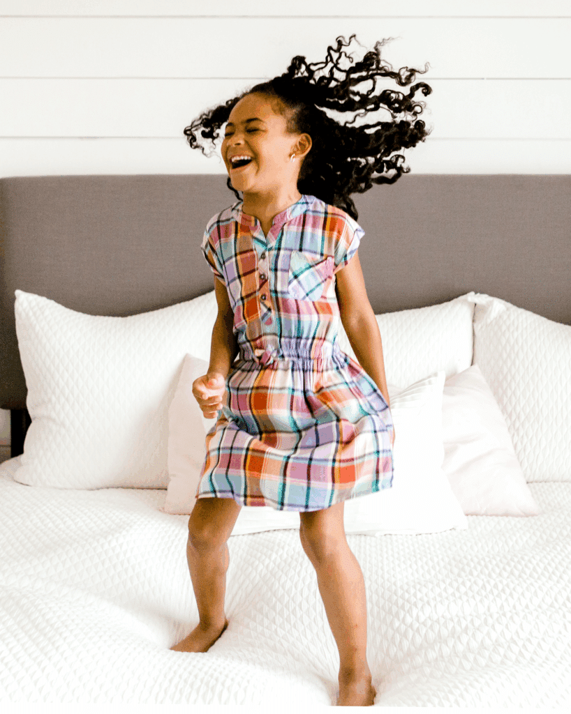 little girl jumping on a bed